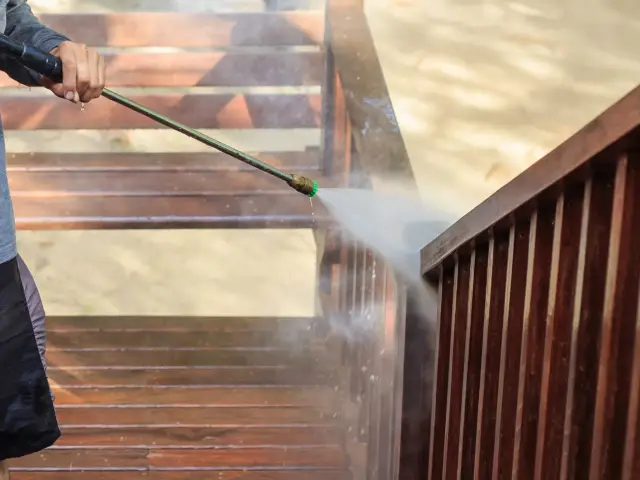 A man power washing the stairs of a porch